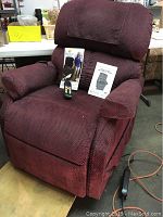 Maroon Golden power lift and recline chair shown with owner's manual and remote on the seat.
