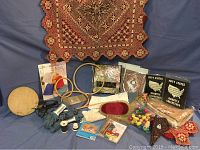 Display of various sewing and hobby items including quilted textile, wooden and metal embroidery hoops, sewing threads, needles, buttons, and collectible quarter collections.