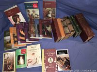 Lot of approximately 19 books laid out on blue background, featuring titles by Jane Austen, Thomas Hardy, Charles Dickens, and more, including paperbacks and hardcover editions.