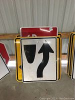 Front view of street signs stacked showing directional symbols and visible wear