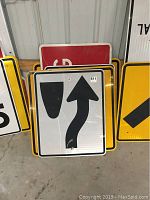 Metal street signs arranged in a stack with a right lane ends sign and other yellow warning signs visible.