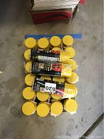 Top view of 27 yellow capped cans of Dow Great Stuff arranged on the floor