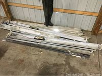 Photo showing multiple fluorescent light fixtures stacked on the floor, some with wiring visible, next to a pair of boots for scale.