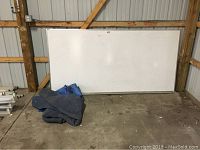 Full view of the large Quartet dry erase board leaning against a wall, showing dimensions and board surface condition.