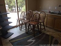 Six wooden barstools arranged in kitchen area showing overall condition and size.