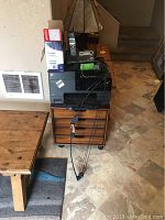 Overall view of lot with HP printer on wood rolling drawer unit, phone system on top, bow hanging beside.