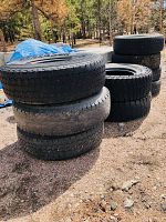 View of stacked tires outdoors showing used condition.
