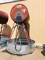 Full view of red steel cylindrical tank labeled "DIESEL" mounted on red steel stand above galvanized spill pool, hoses visible