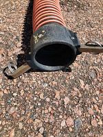 Photo of one end of the red corrugated septic hose with black camlock fitting attached.