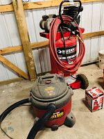 Shop-Vac wet/dry vacuum and Husky Pro air compressor side by side on concrete floor, plus bottle jack box