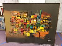 Full view of large framed abstract mixed media wall art with vibrant color blocks and grid lines on dark background.