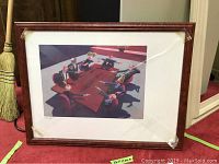 Framed signed print depicting men around a table. Frame has tape across length and corner wear.
