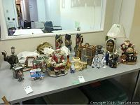 Wide view of shelf displaying multiple figurines, a lamp, ceramic miniatures, and decorative items