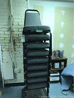 Stacked view of nine gray fabric office chairs with black metal frames.