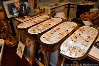 Four lacquered relief art panels displayed on a table with other art pieces around them, showing full set and overall size.