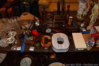 Top view of multiple collectibles on tables including clocks, awards, gavels, and decor items.