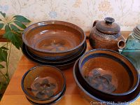 Seven-piece Quay Pottery stoneware set with teapot, bowls, pie plate, and serving dishes arranged on a wooden surface.