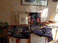 Overview of two textiles including black and white elephant tapestry, colorful Guatemalan woven fabric, framed papyrus picture, and additional woven baskets visible