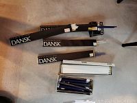 Dansk taper candles in black packaging with white labels, mixed lengths and colors, arranged on carpeted floor
