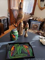 Four Costa Rican wood items on a table: large balsa wood parrot, small parrot, painted tray and painted urn visible