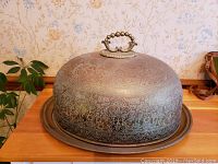 Overall view of the brass turkey platter with its domed cover showing engraved floral patterns and handle