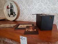 Photo showing the antique No. 2 Brownie Camera, three old photographs laid out, and the Norman Rockwell plate propped up behind them.