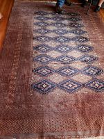 Full view of the large rectangular area rug laid on wooden floor with visible diamond pattern and brown border.
