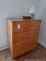 Front and angled front view of Mid Century Modern wooden dresser with 4 drawers, showing style, wood finish, and condition.