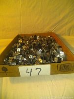 Box filled with approximately 300 metal male Jones four-pin connectors showing many connectors piled in a cardboard box.