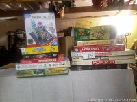 Photo showing stacked board games including Monopoly sets, Dominoes, Chess, Slot Shot and Gravity Maze