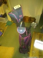 Photo showing golf bag upright with multiple clubs inside including headcovered woods and irons.