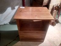 Front view of wooden microwave cabinet showing two open shelves and wood grain finish.
