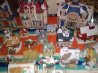 Top-down photo showing multiple miniature Christmas village buildings with snow roofs, colorful detailing, and festive holiday decorations.