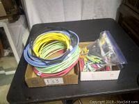 Various rolls of multicolored shrink wrap tubing arranged on a table with a box containing various small electrical connectors or terminals.