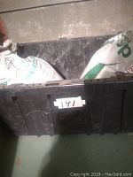 Black plastic bin containing the two bags of soil additives: opened Azomite bag and unopened Epsotop bag.