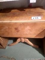 Vintage wooden drop leaf table with leaves down, showing wood finish and base detail
