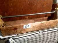 Wooden carpenter's tool box with large metal bar across the top and visible interior compartments