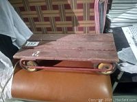 Top and side view of wooden platform on red metal frame with four yellow wheels.