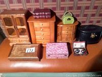 Photo showing seven distinct jewelry boxes and a small box with two metal relaxation balls arranged on a table.
