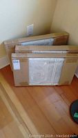 Photo of three boxed IKEA Lennart storage carts stacked upright against wall with visible packaging and label.
