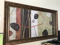 Full view of the abstract painting with geometric shapes and a large wood-tone frame.
