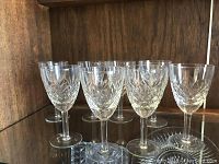 Picture of 6 crystal wine glasses with diamond-cut pattern standing on a wood shelf