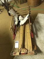 Full view of the wooden Torpedo sleigh with red metal runners with one pair of white ice skates on top
