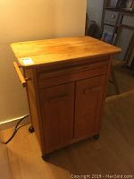 Full view of wooden kitchen island with butcher block style top, closed drawer and cabinet doors.