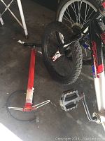 Photo of Trail Blazer bike's front wheel, pedal, and a red bike pump on the floor