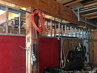 Side view of the aluminum extension ladder hanging horizontally against a wall, orange extension cord also visible nearby.