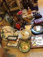 Photo showing an overall view of the lot with various bowls, plates, teapot, cinnabar box, and decorative items arranged on the floor.
