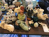 Wide view of assortment of ceramic animal figurines including cats, dogs, duck, squirrel, and deer displayed on table.
