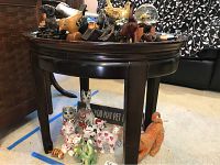 Oval wooden table with dark finish, displaying an assortment of decorative animal figurines on and around it.