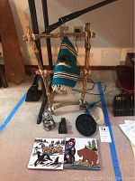 Full view of all items in lot including wooden stand with woven textile, two decorative tiles, stone carved figurines and carved black object.